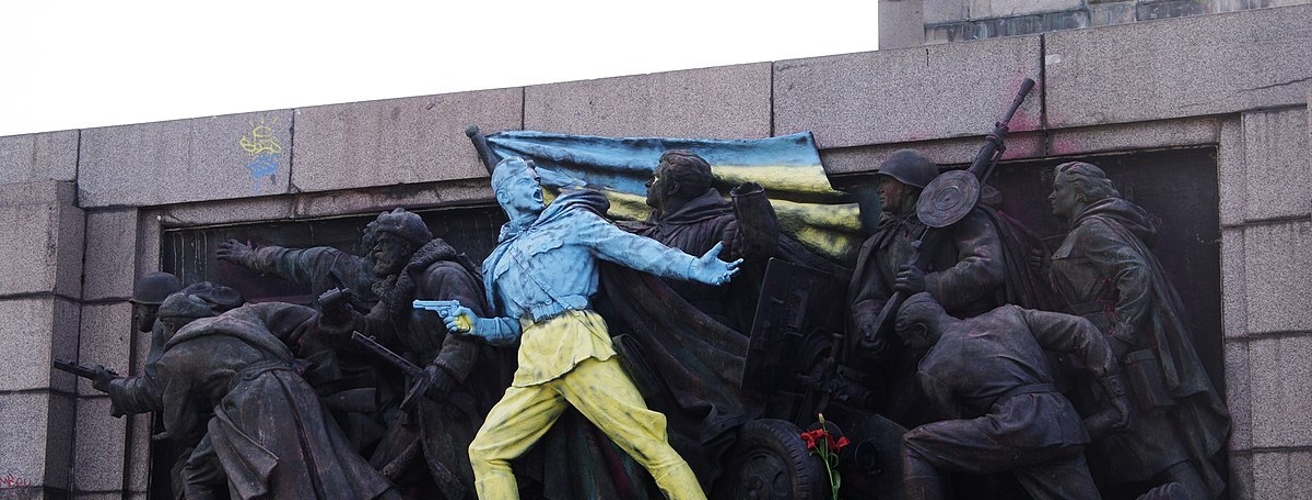 Historical Soviet Plastic depicts a soldierly, heroic scene. The flag is painted over in Ukrainian colors.